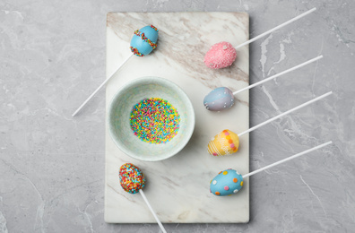 Photo of Egg shaped cake pops for Easter celebration on grey marble table, flat lay