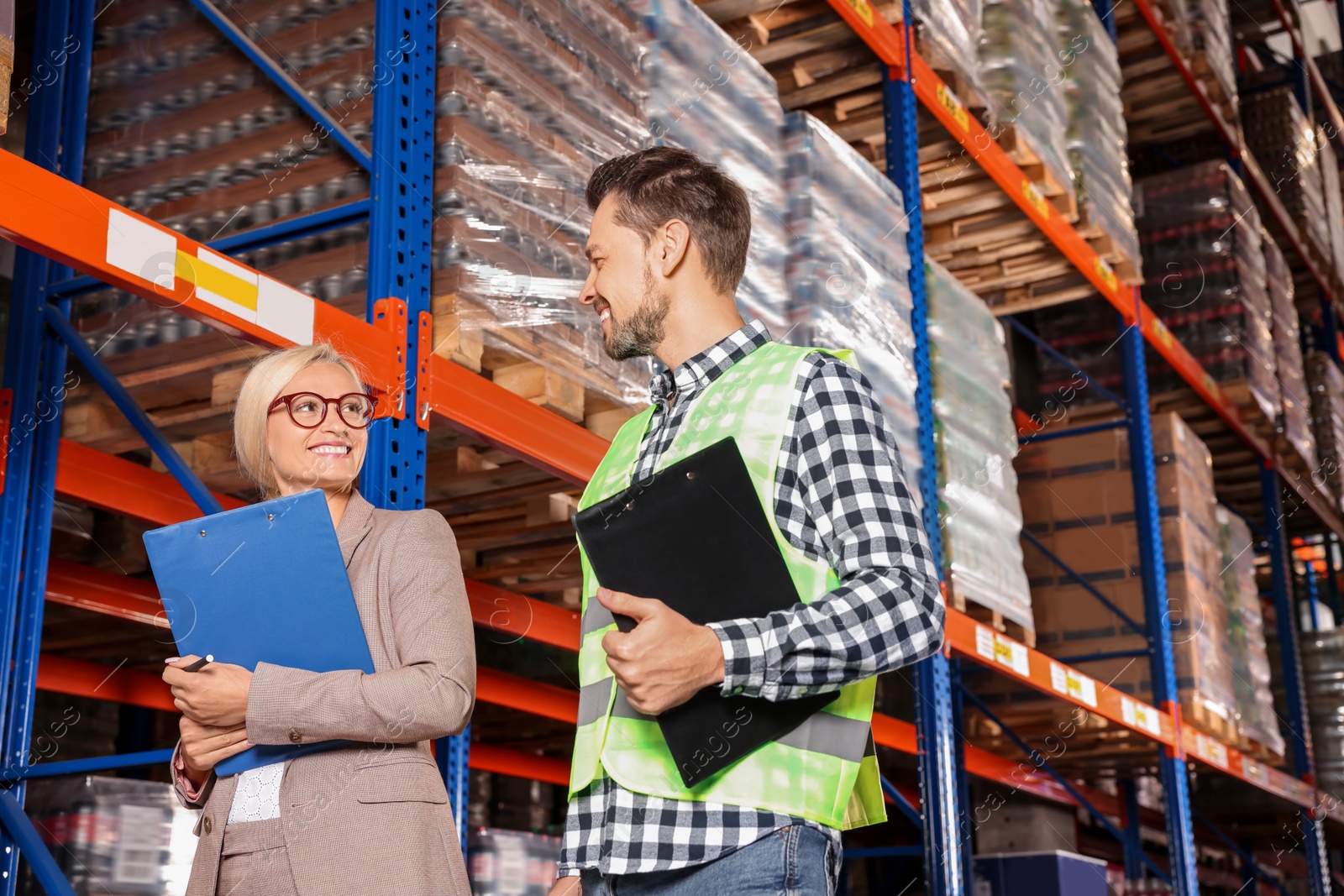 Photo of Manager and worker in warehouse with lots of products