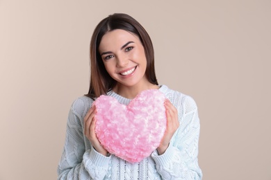 Photo of Portrait of woman with decorative heart shaped pillow on color background