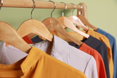 Photo of Collection of trendy women's garments on rack near green wall, closeup. Clothing rental service