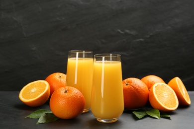 Photo of Delicious orange juice and fresh fruits on black table