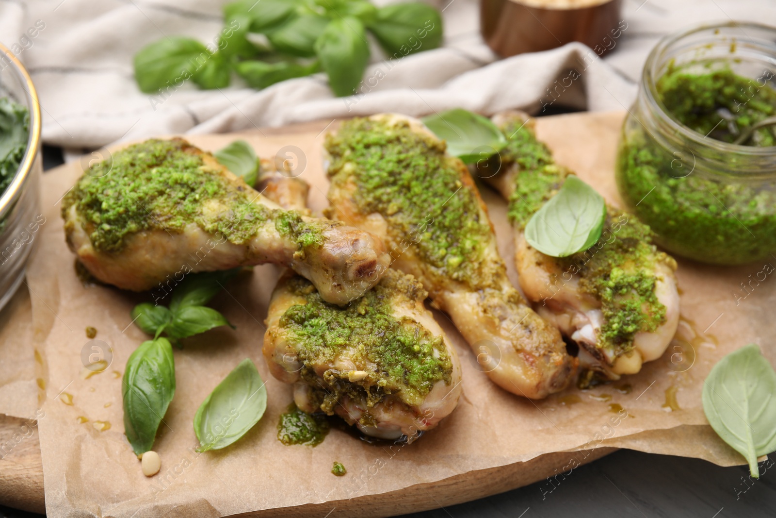 Photo of Delicious fried chicken drumsticks with pesto sauce and basil on table, closeup