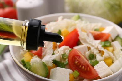 Photo of Adding cooking oil to tasty salad with Chinese cabbage at table, closeup