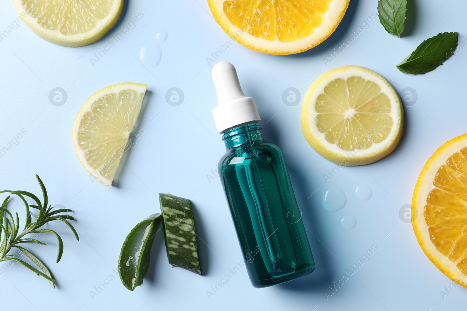 Photo of Bottle of cosmetic serum, sliced citrus fruits and different plants on light blue background, flat lay