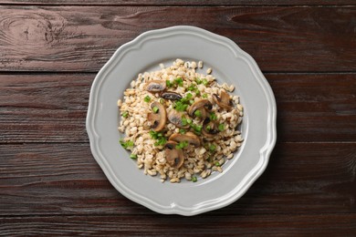 Photo of Delicious pearl barley with onion and mushrooms on wooden table, top view