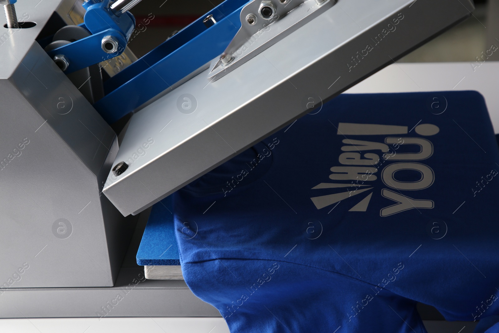 Photo of Printing logo. Heat press with blue t-shirt on table, closeup