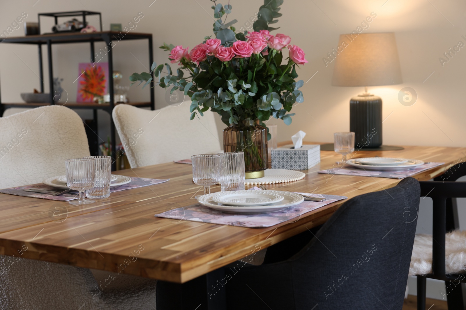 Photo of Beautiful table setting with bouquet indoors. Roses and eucalyptus branches in vase