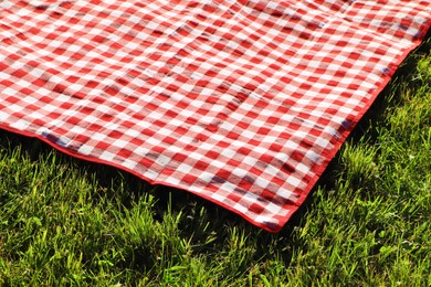 Photo of Checkered picnic tablecloth on fresh green grass outdoors