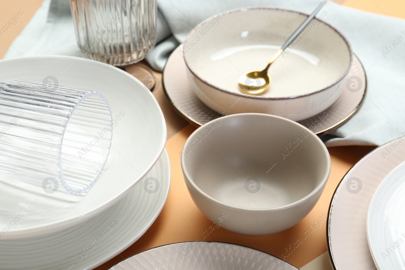 Photo of Clean plates, bowls and spoon on table, closeup