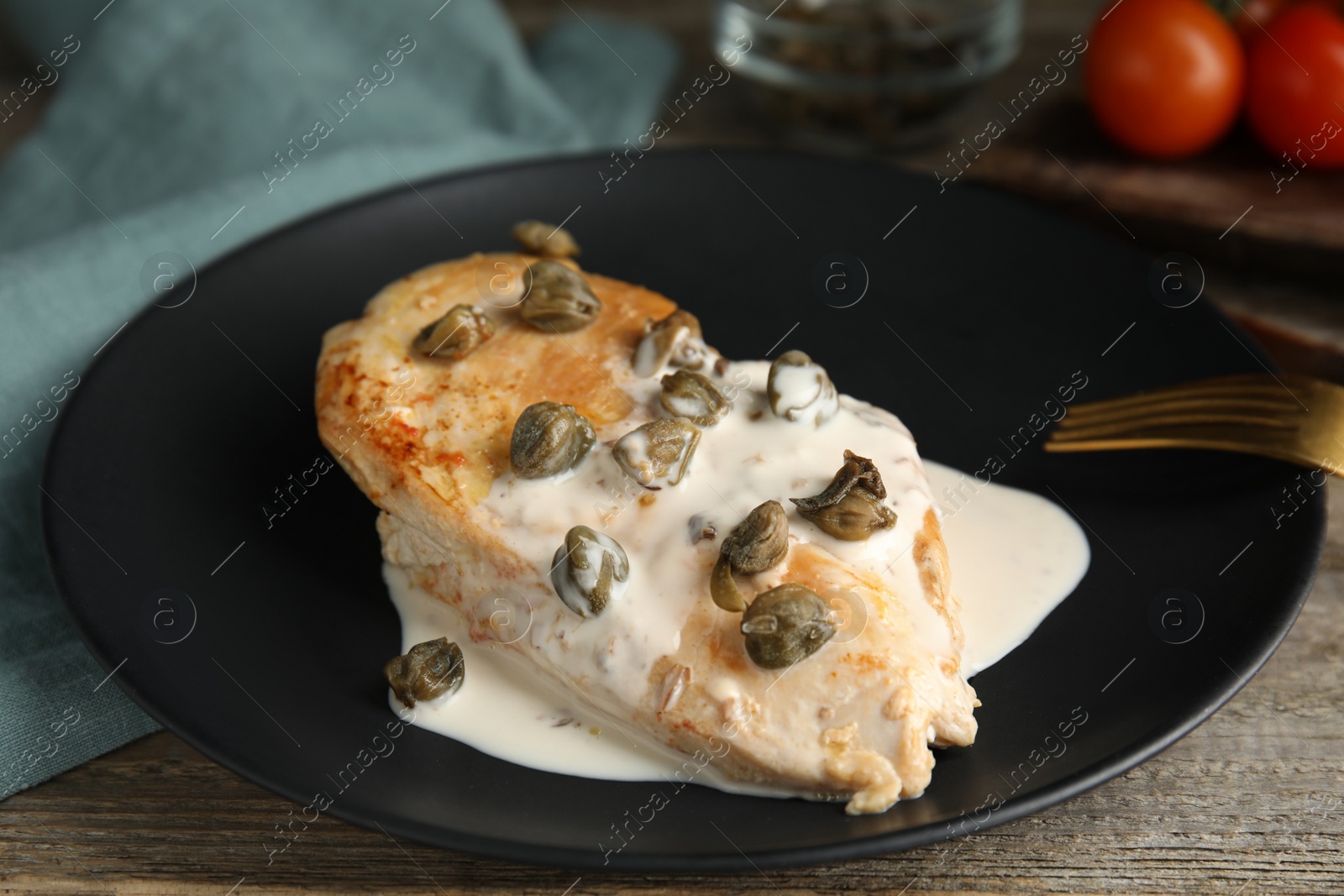 Photo of Delicious chicken fillet with capers and sauce served on wooden table, closeup