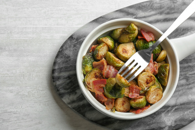 Photo of Roasted Brussels sprouts with bacon served on white wooden table, top view