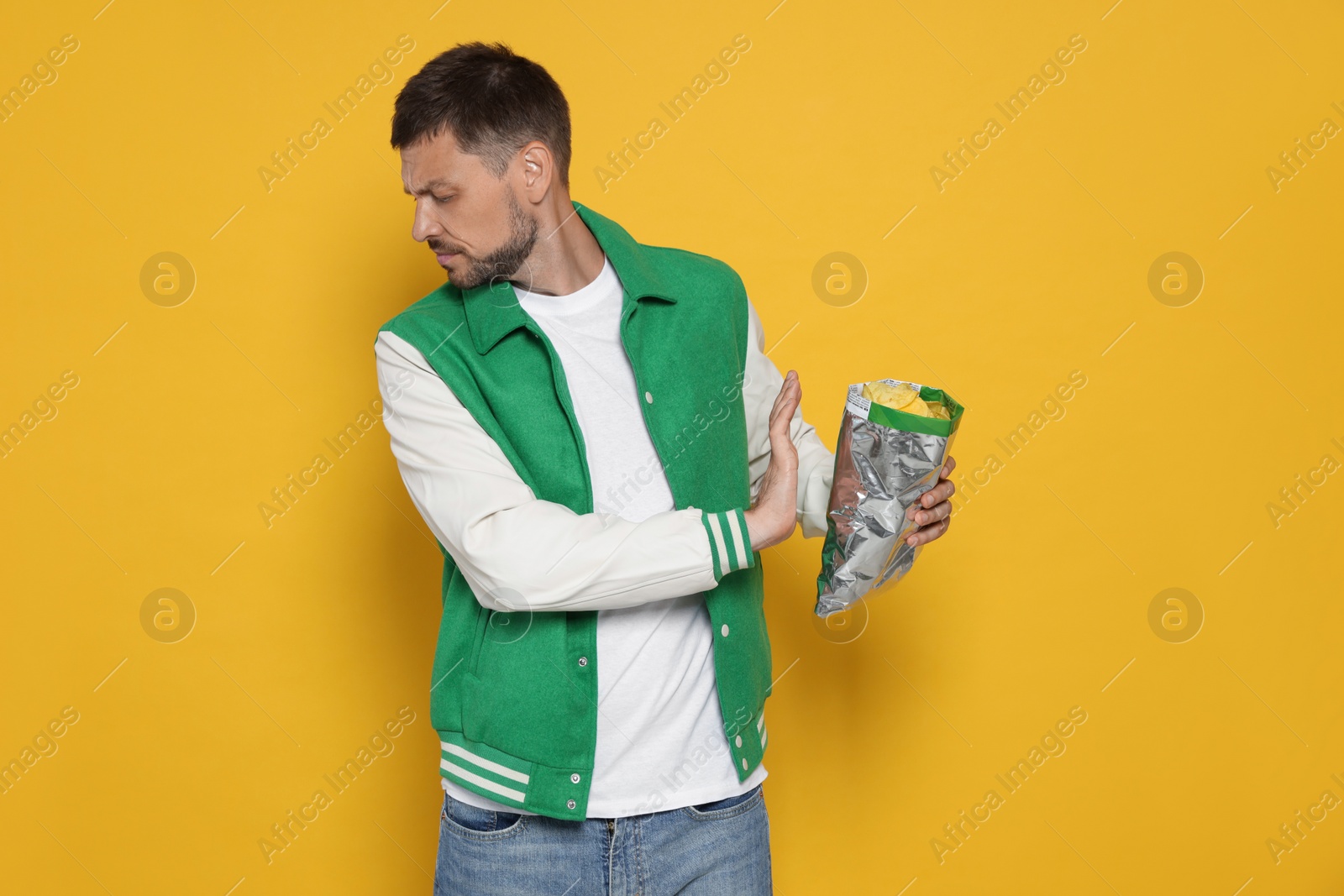 Photo of Handsome man refusing to eat potato chips on orange background