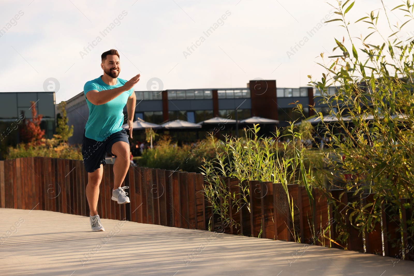 Photo of Smiling man running outdoors on sunny day. Space for text