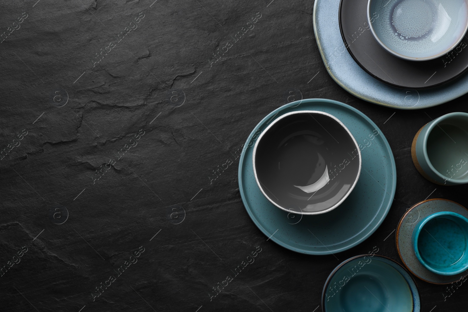 Photo of Set of clean tableware on black table, flat lay. Space for text