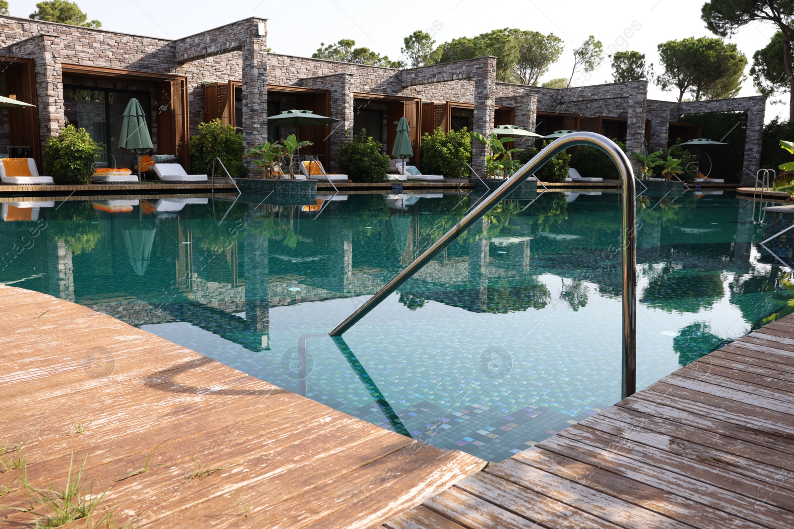 Photo of Wooden deck, swimming pool and metal rail at luxury resort