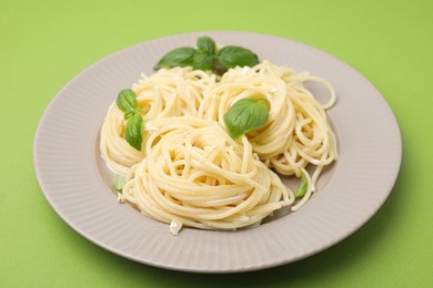 Photo of Delicious pasta with brie cheese and basil leaves on green table, closeup