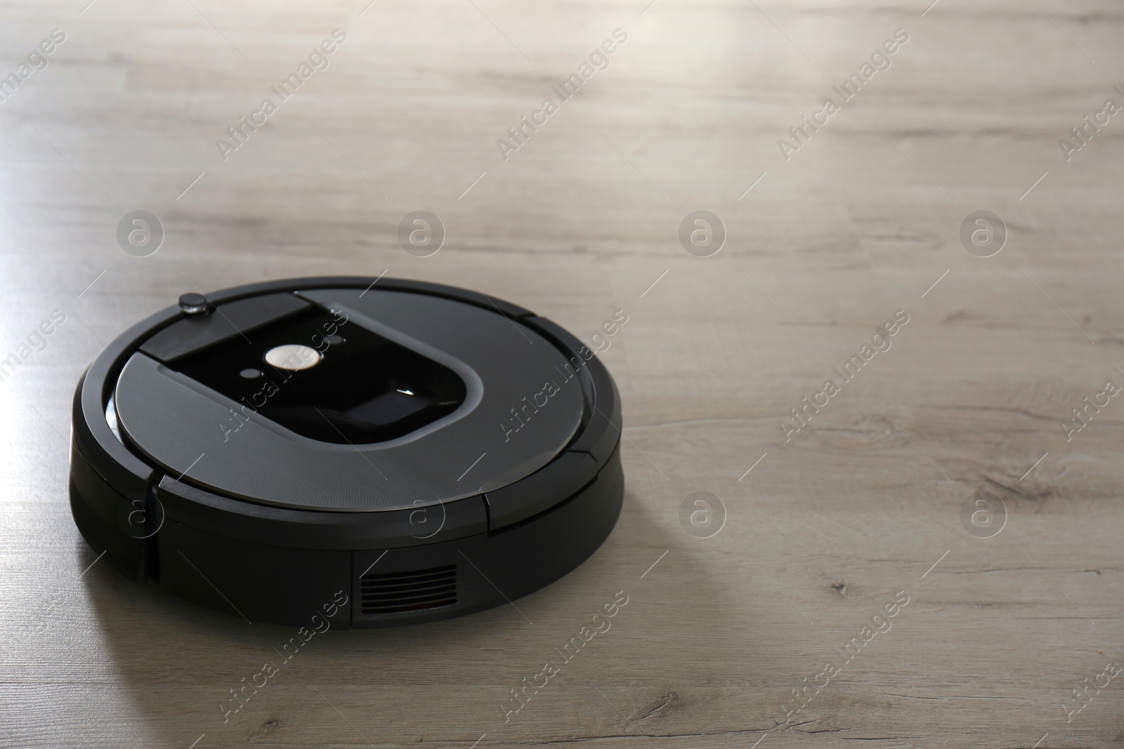 Photo of Modern robotic vacuum cleaner on wooden floor. Space for text