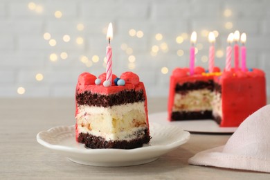 Photo of Piece of bento cake with tasty cream and burning candles on wooden table, closeup