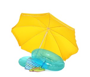 Photo of Open yellow beach umbrella, inflatable rings, blanket and flip flops on white background