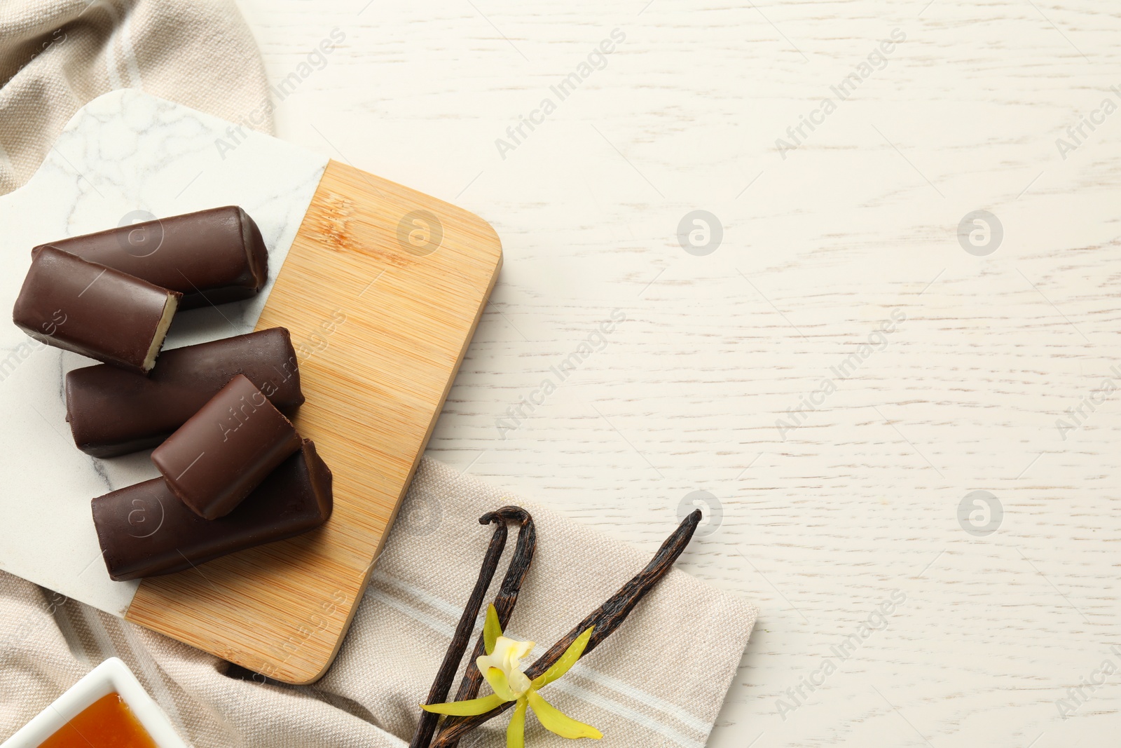 Photo of Glazed vanilla curd cheese bars on white wooden table, flat lay. Space for text