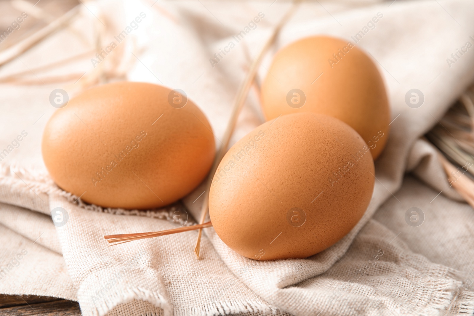 Photo of Raw brown chicken eggs on sackcloth, closeup view