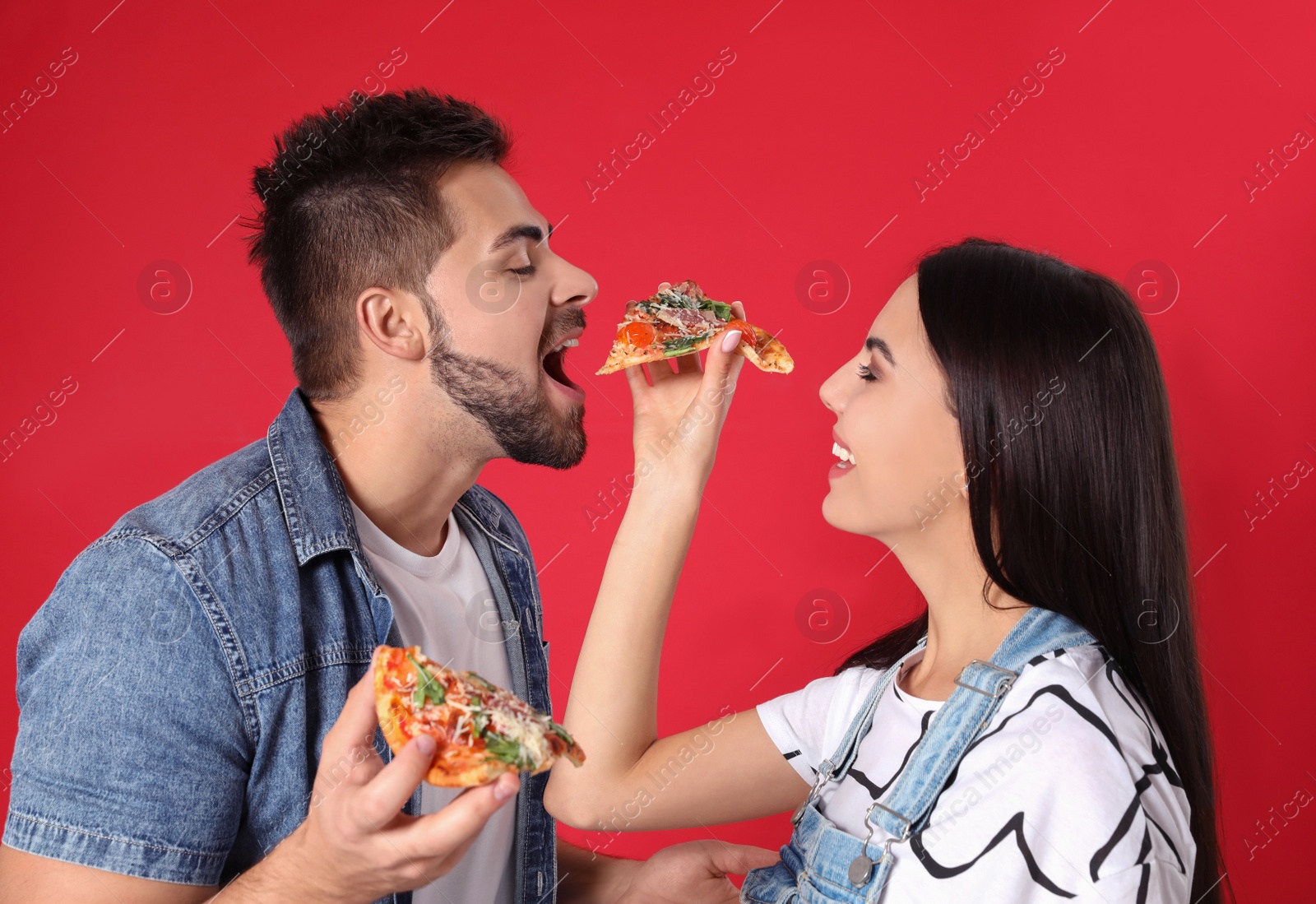 Photo of Happy young couple with pizza on red background