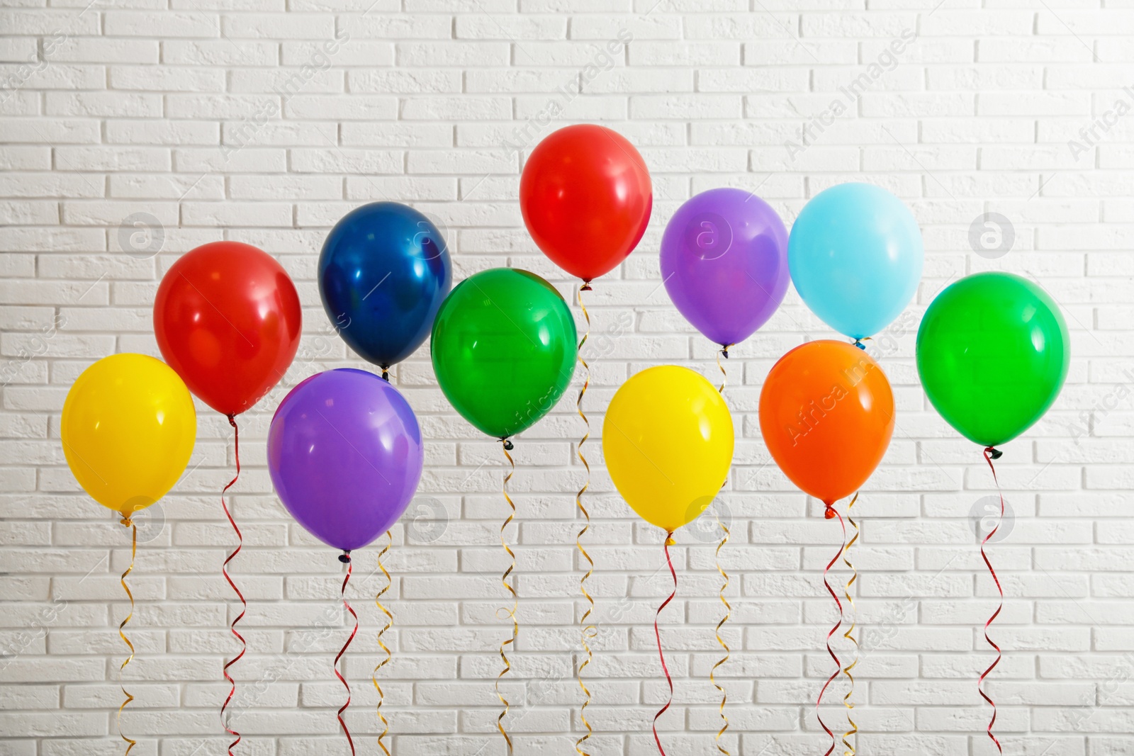 Photo of Bright balloons near brick wall. Celebration time