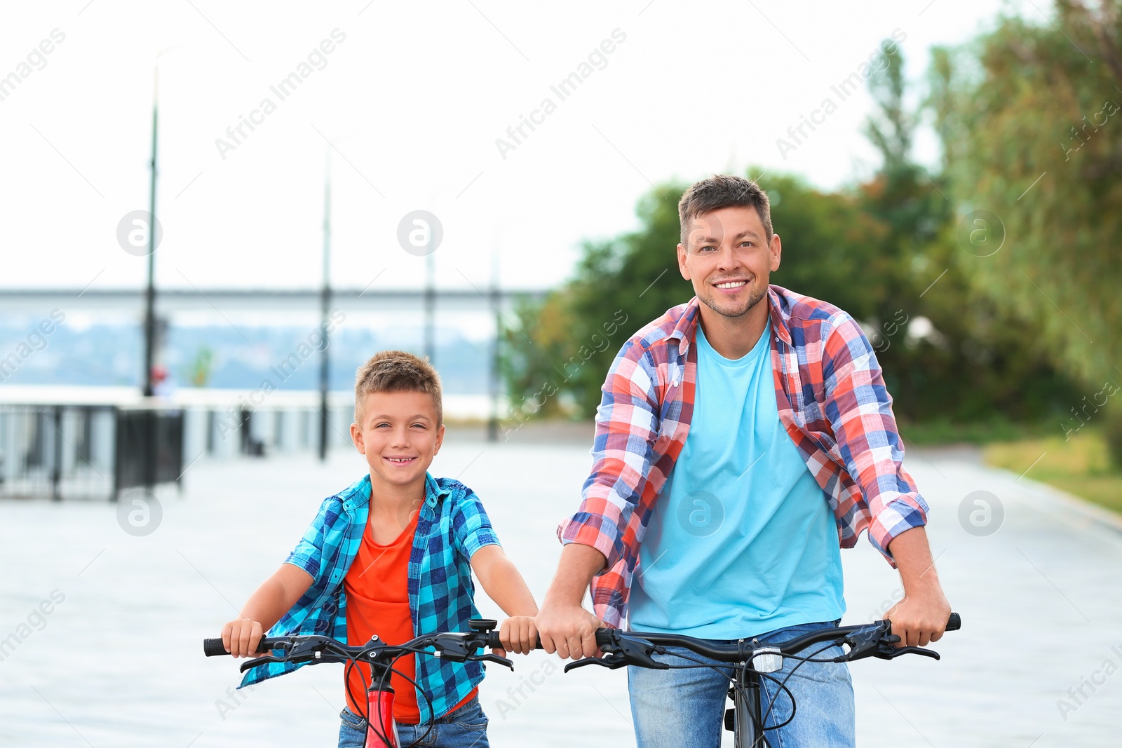 Photo of Dad and son riding bicycles together outdoors