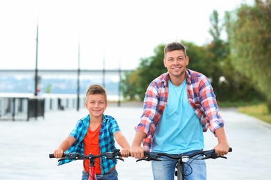 Photo of Dad and son riding bicycles together outdoors