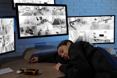 Female security guard sleeping near monitors at workplace