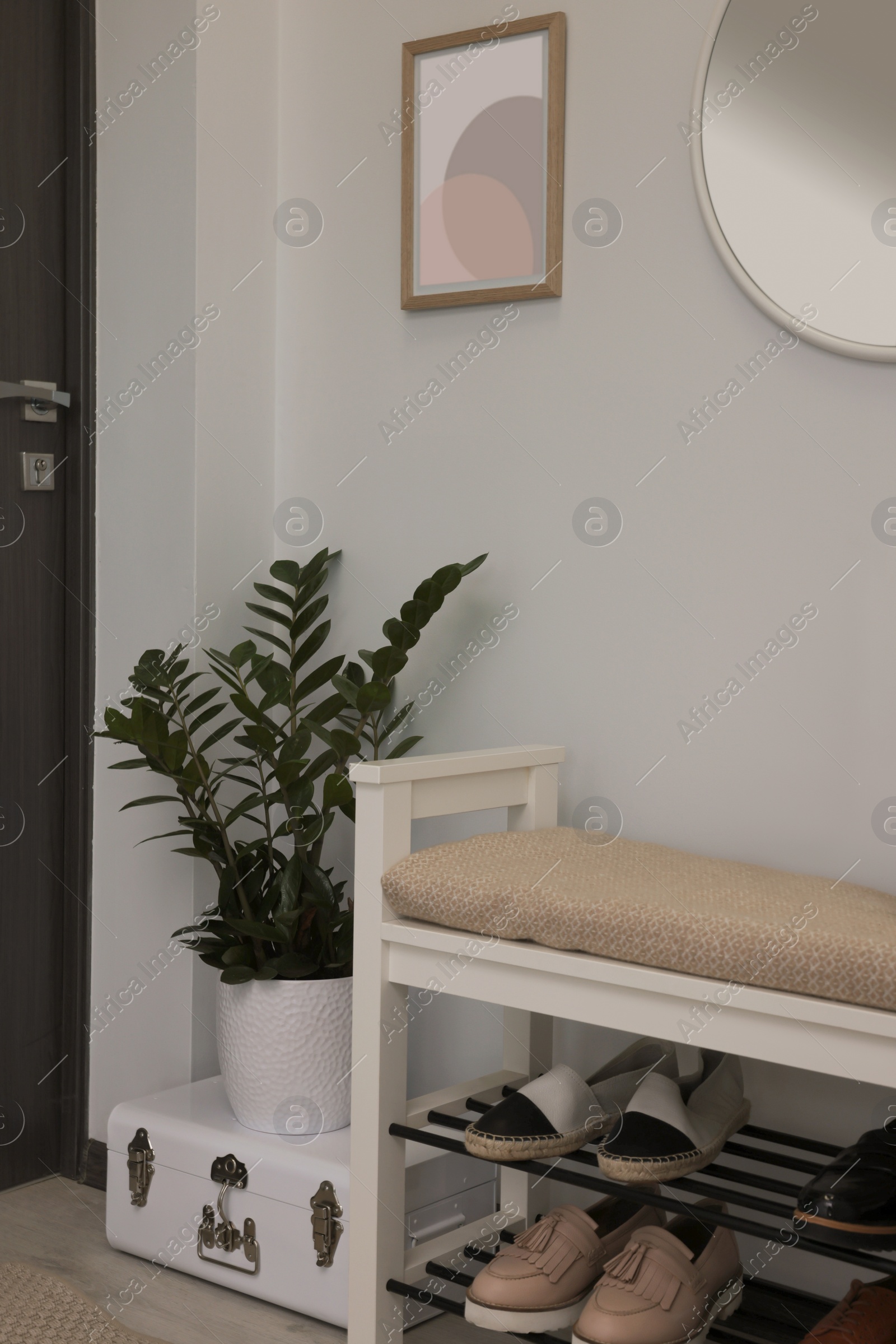 Photo of Stylish hallway room interior with bench, shoes and round mirror