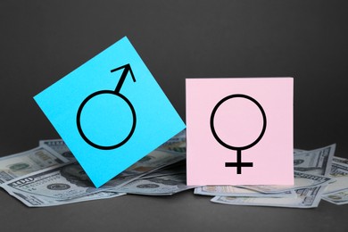 Photo of Gender pay gap. Male and female symbols on dollar banknotes against black background