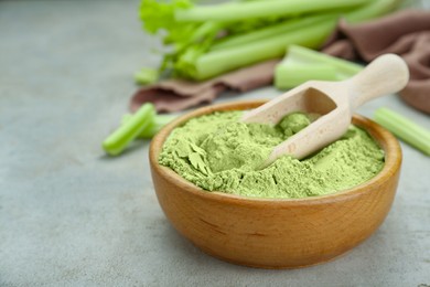 Photo of Wooden bowl and scoop with natural celery powder on grey table, closeup. Space for text