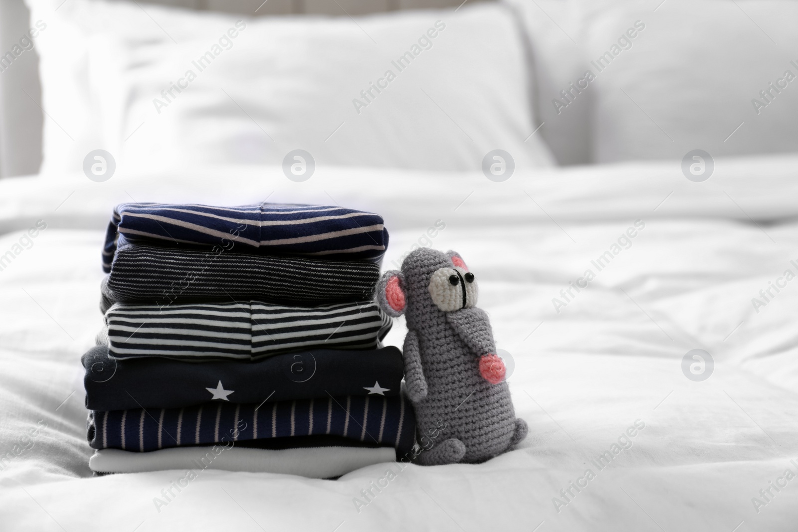 Photo of Stack of clean baby's clothes and toy on bed