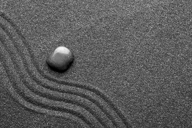 Zen garden stone on black sand with pattern, top view