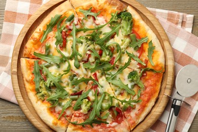 Photo of Board with delicious vegetarian pizza on wooden table, top view