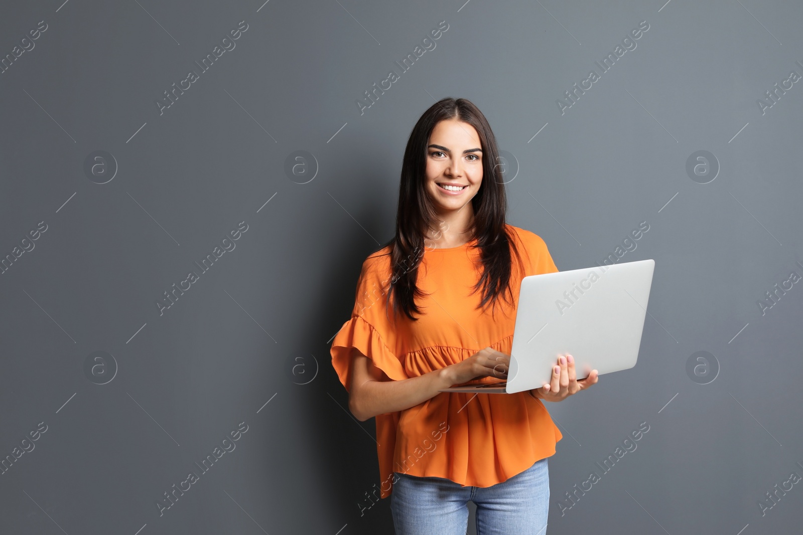 Photo of Young woman with modern laptop on grey background