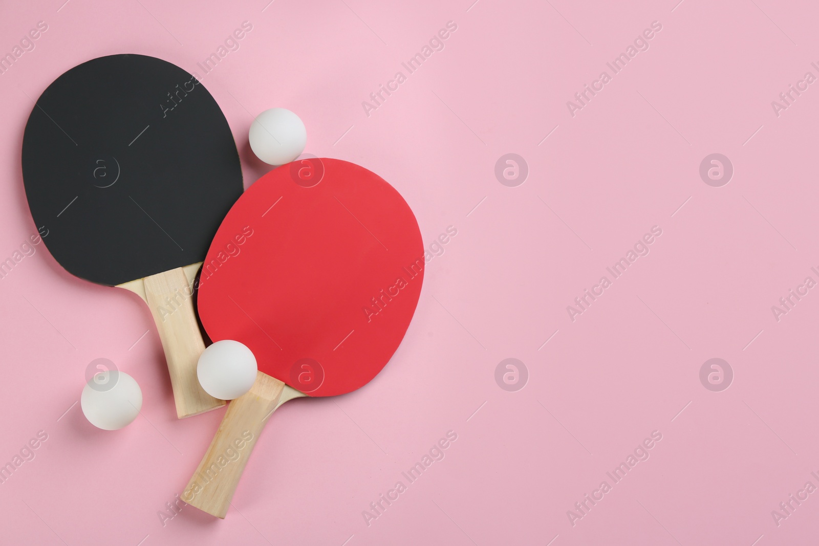 Photo of Ping pong rackets and balls on pink background, flat lay. Space for text