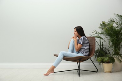 Young woman relaxing on chair at home, space for text