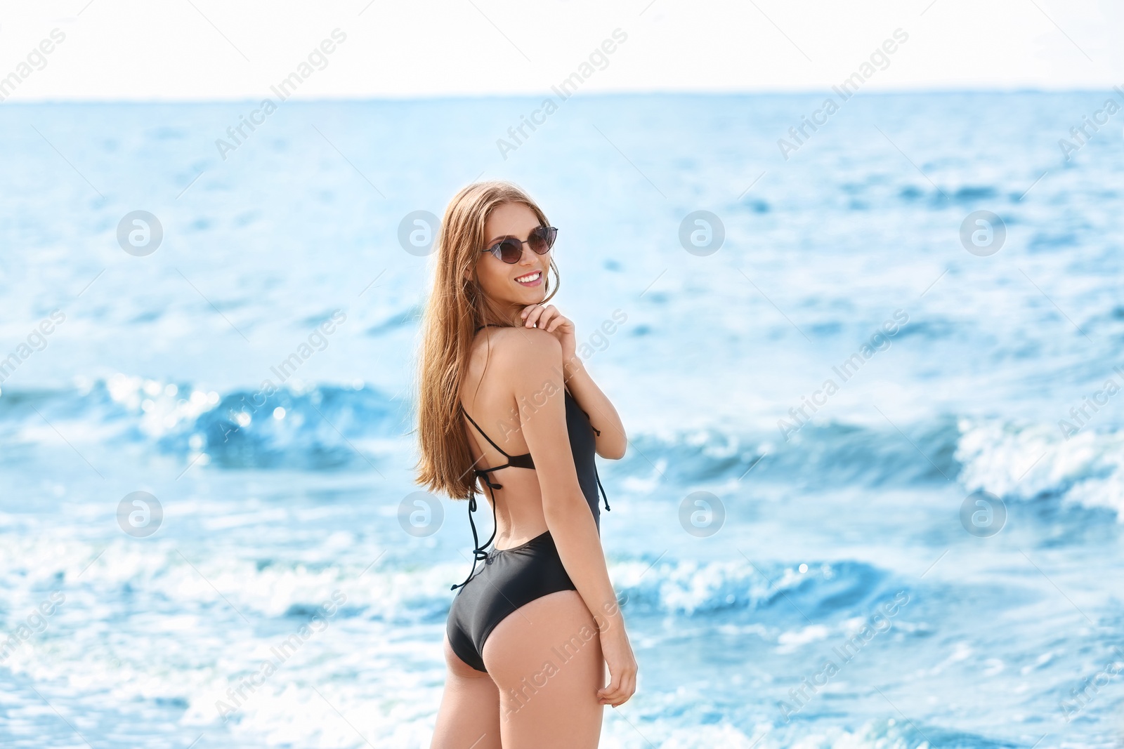 Photo of Attractive young woman in beautiful one-piece swimsuit on beach