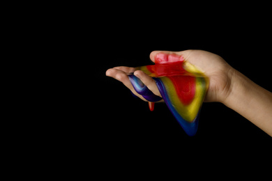 Photo of Woman playing with colorful slime on black background, closeup. Antistress toy