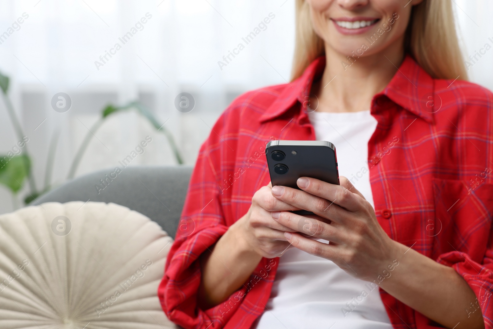 Photo of Woman sending message via smartphone at home, closeup