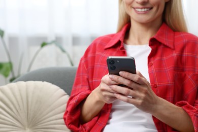 Photo of Woman sending message via smartphone at home, closeup