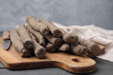 Photo of Raw salsify roots on grey wooden table, closeup