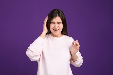 Portrait of stressed young woman on purple background