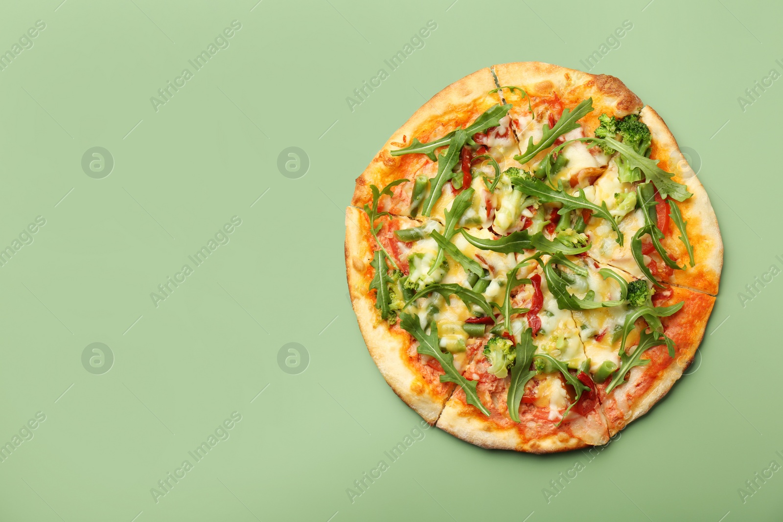 Photo of Delicious vegetarian pizza on green table, top view. Space for text