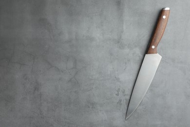 Photo of One knife on grey textured table, top view. Space for text