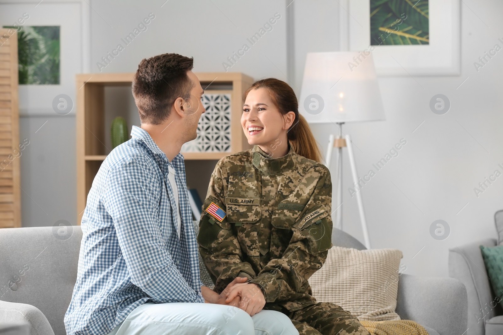 Photo of Woman in military uniform with her husband on sofa at home