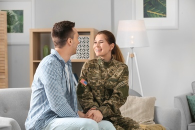 Woman in military uniform with her husband on sofa at home