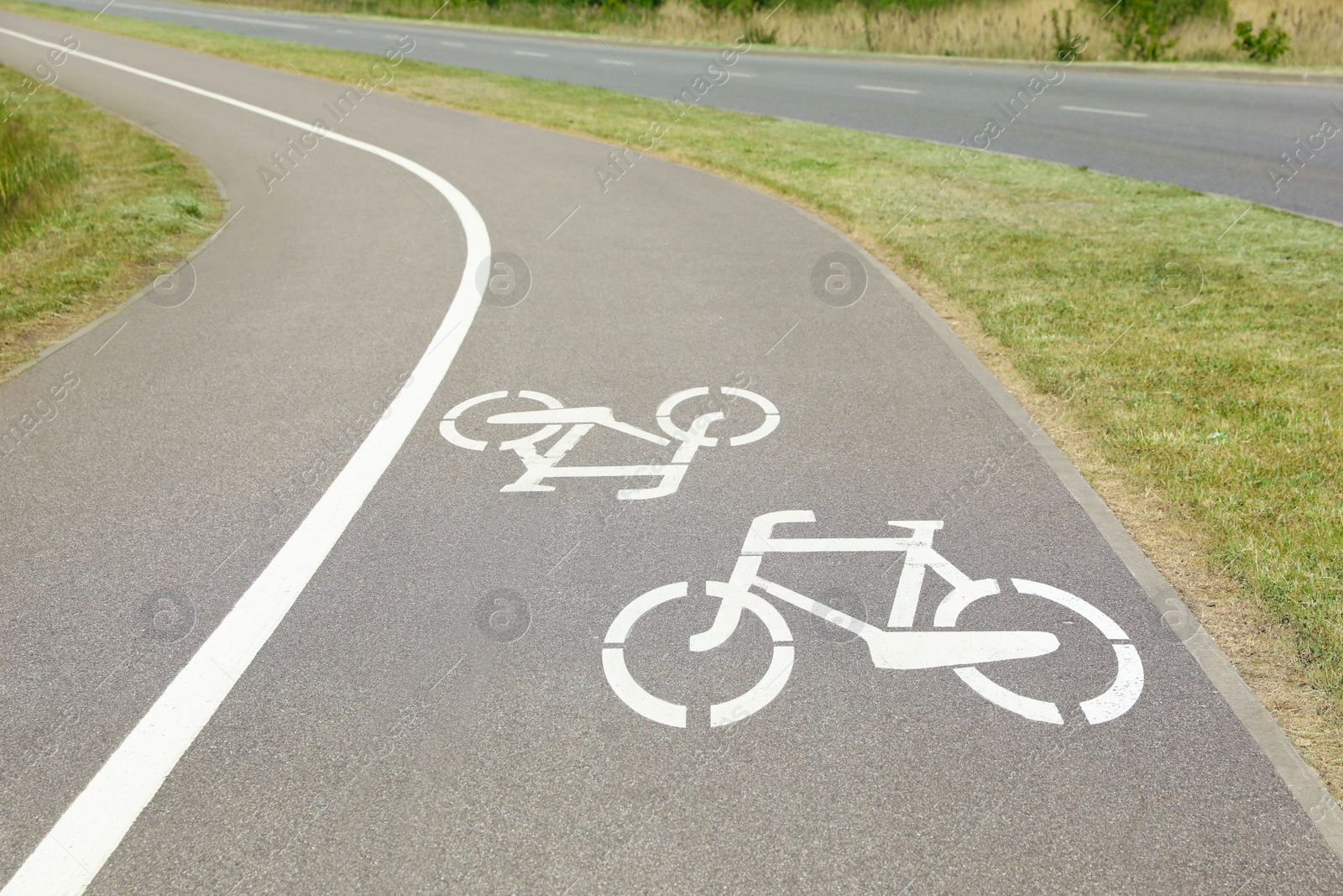 Photo of Bicycle lane with white sign painted on asphalt near sidewalk